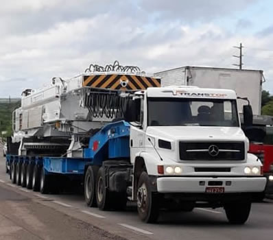 Carreta prancha transportando máquina pesada